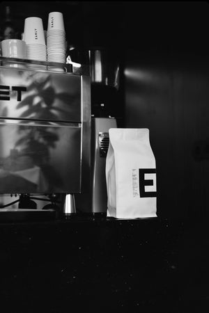 E1 Espresso Blend Coffee bag with a brand logo next to a Rocket E9 Espresso coffee machine